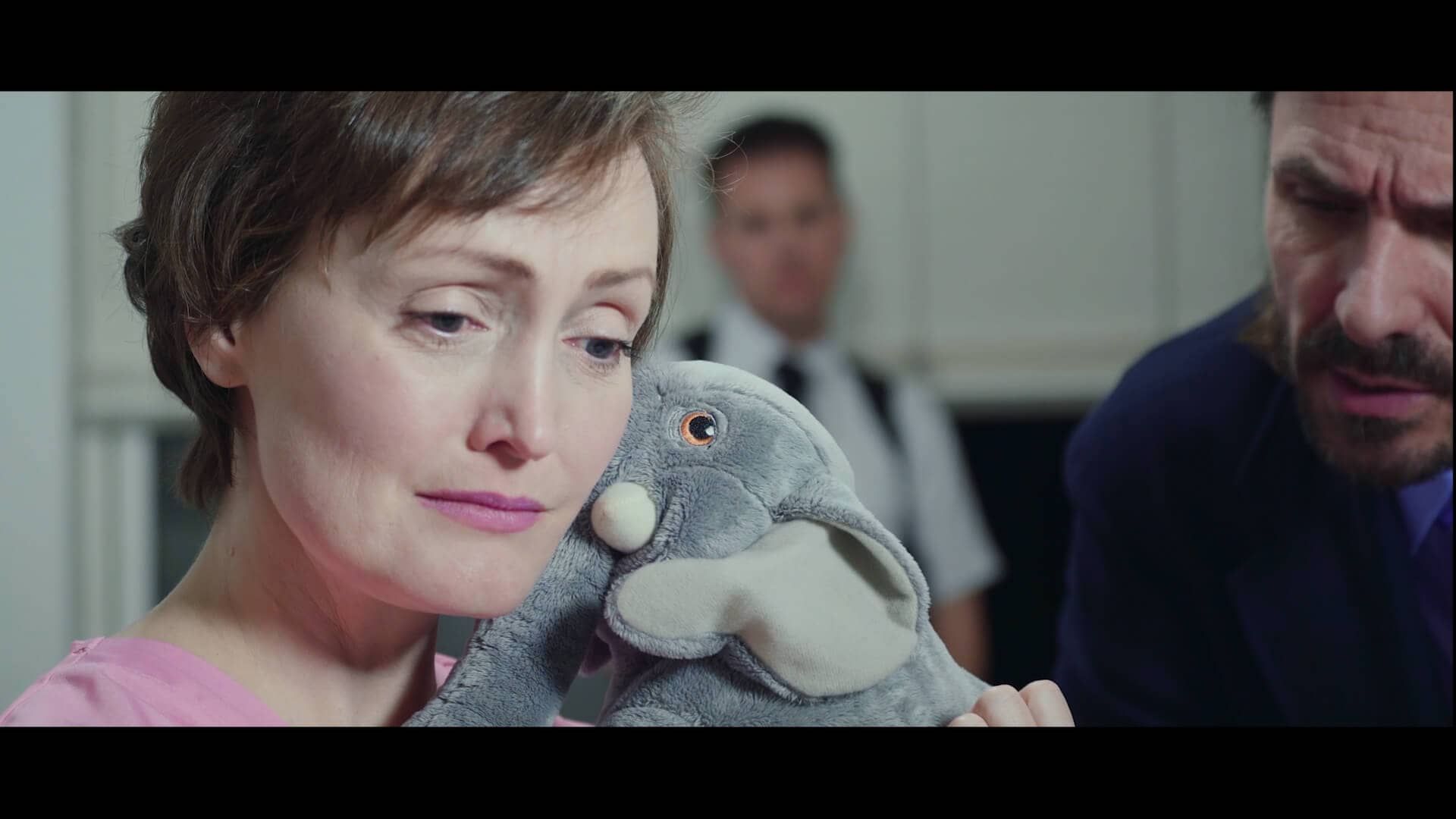 Still from Missing Kitty. Julie-Anne holds a stuffed animal and looks away, on the verge of tears.